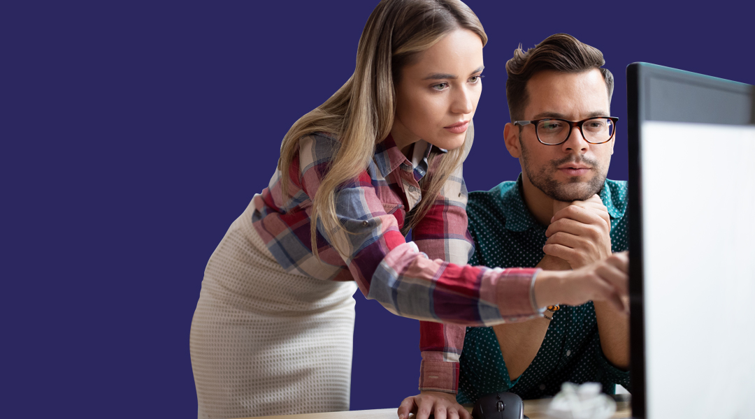 Image of a woman explaining a process to a man at a computer